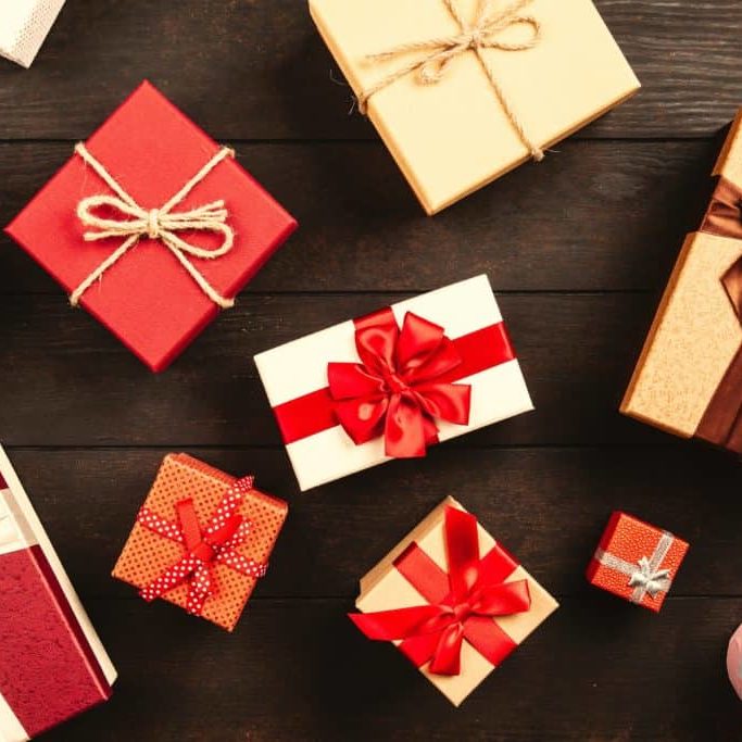 Red and gold holiday gift boxes, scattered on a brown wooden surface