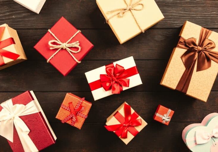 Red and gold holiday gift boxes, scattered on a brown wooden surface